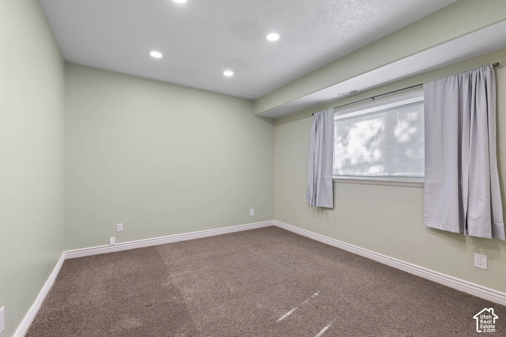 Recessed ceiling lighting, a window with blinds, a carpeted floor, and painted walls