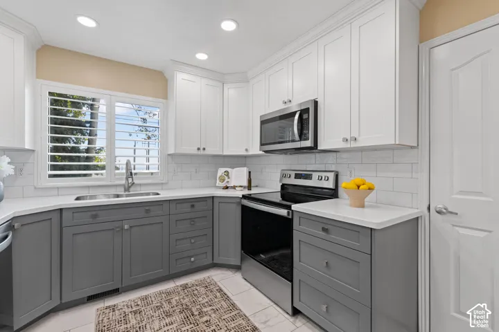 Kitchen featuring two-tone cabinetry, stainless steel appliances, white subway tile backsplash, and recessed lighting