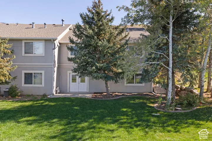 Gray stucco exterior with a light-toned roof, ground-level patio, and multiple windows