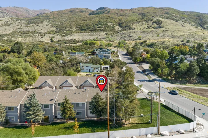 Townhome community nestled in a rolling hillside setting, featuring contemporary architectural design with peaked rooflines, manicured landscaping with mature trees, and a gated entry