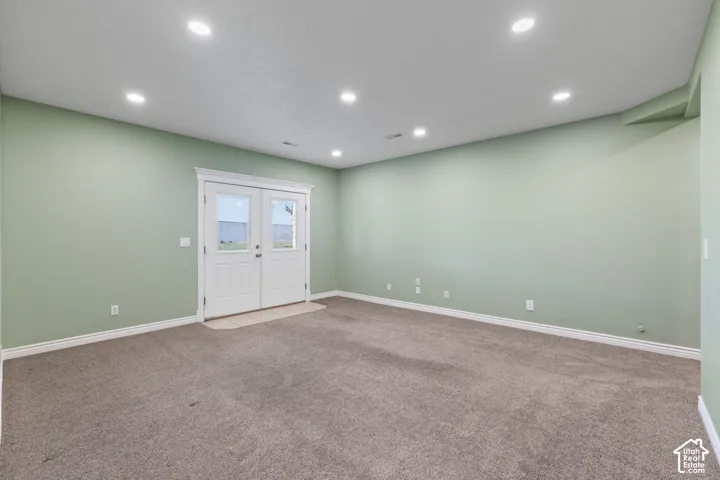 Recessed lighting, French doors with glass panels, light-colored carpeting, white trim, and a neutral wall color