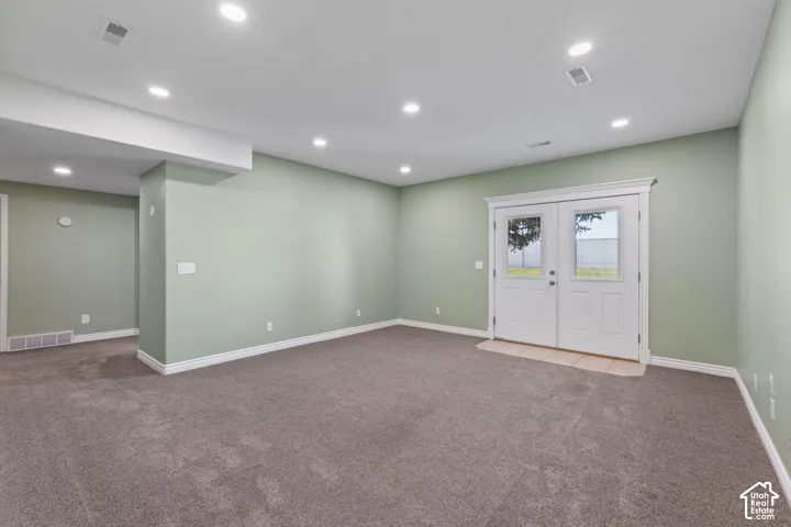 Recessed ceiling lighting, light green wall paint, gray carpet flooring, white trim, and white French doors with glass panels