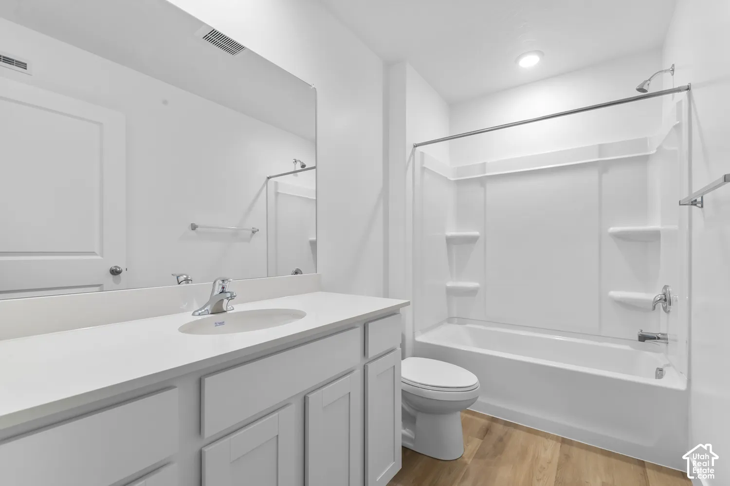 White vanity with integrated sink, chrome faucet, and a large wall-mounted mirror