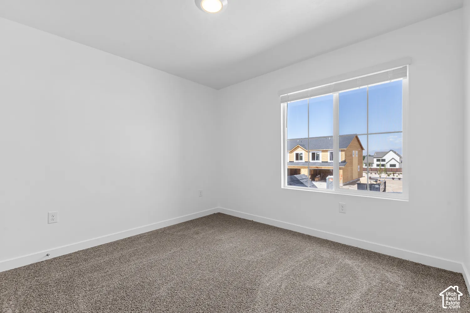Wall-to-wall carpeting, recessed ceiling lighting, and a large window with roller shades