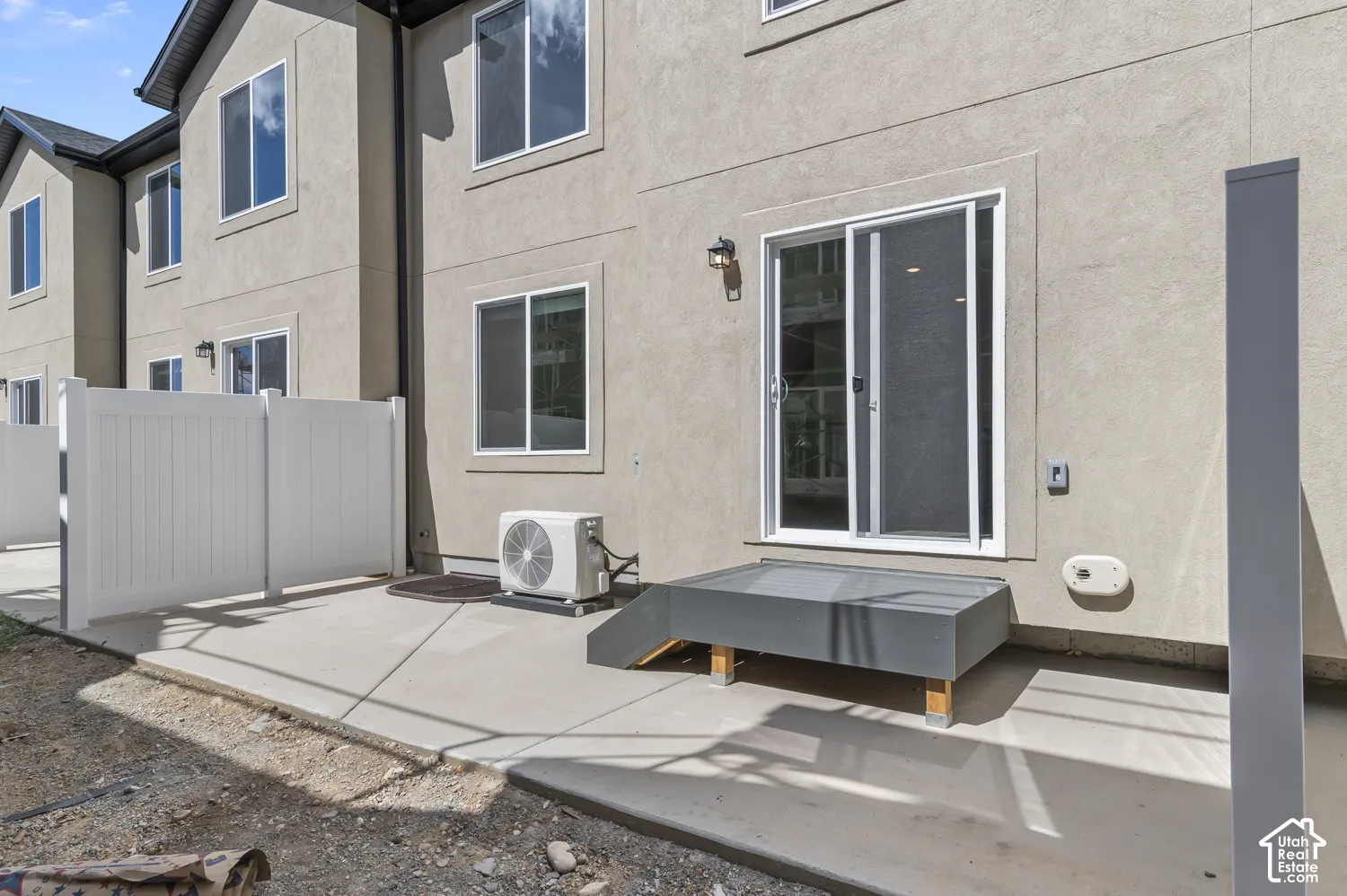 Private patio with concrete surfacing, white vinyl fencing, and direct sliding door access