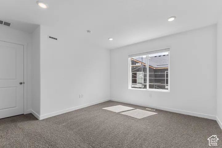 Recessed ceiling lighting, white interior door, light gray carpet, white walls, and a window with blinds