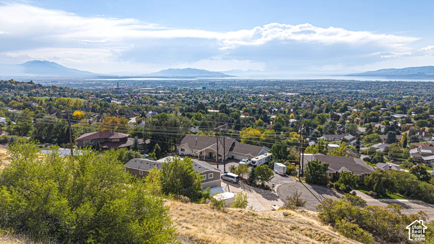 Expansive views of a cityscape, distant lake, and mountain range