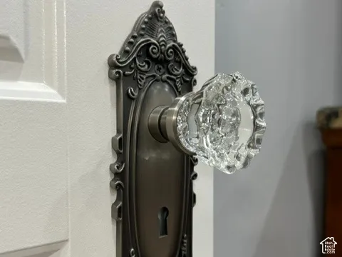 White paneled door featuring an ornate dark bronze escutcheon plate and a clear glass knob