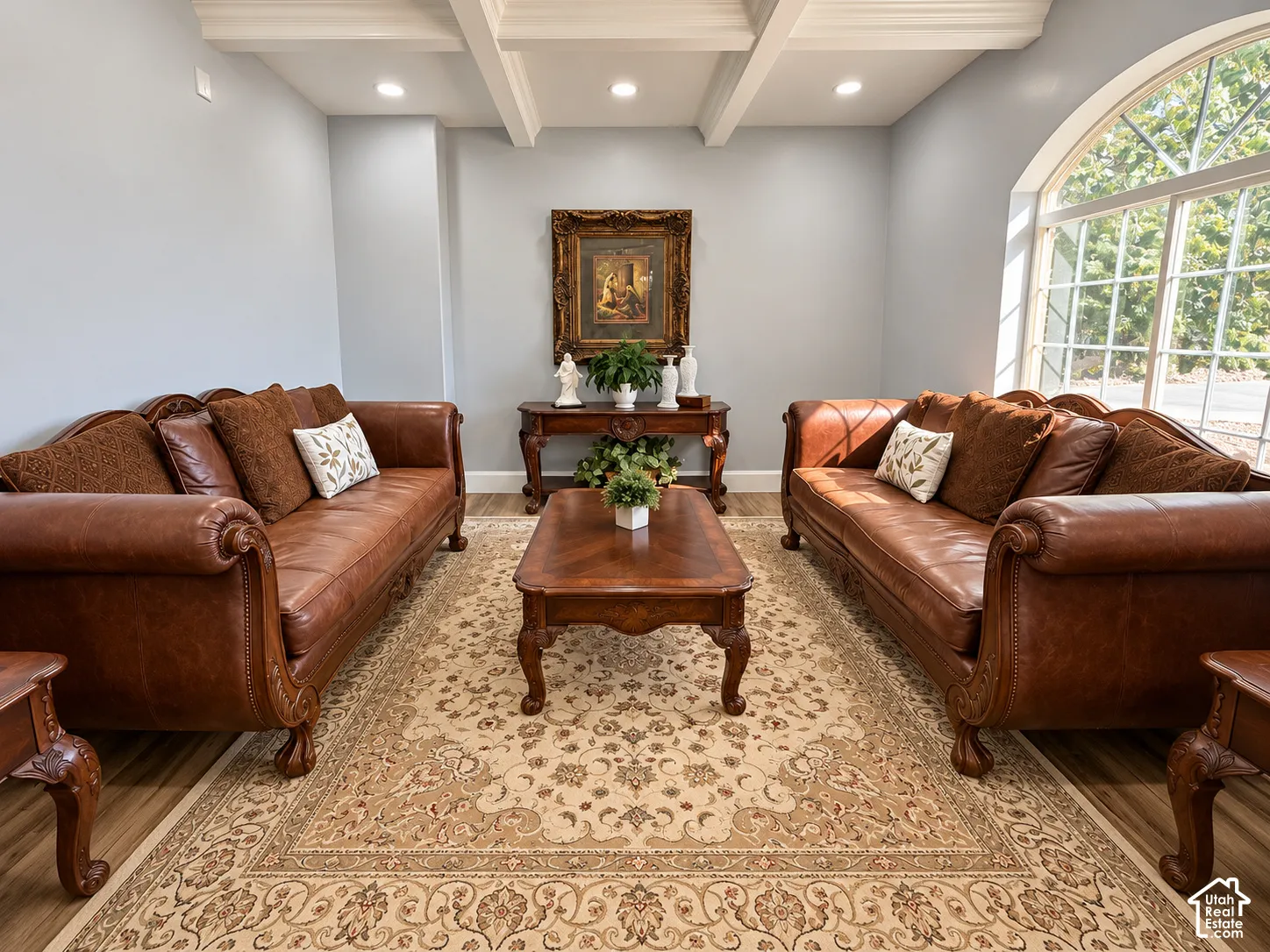 Formal living room showcasing paired leather Chesterfield sofas with rolled arms and nailhead trim, anchored by a wood coffee table with cabriole legs