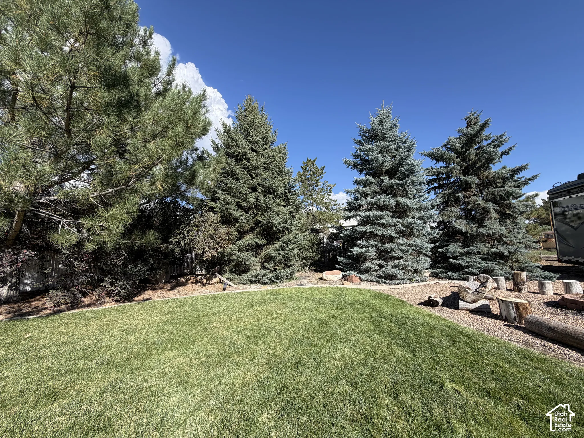 Manicured lawn with mature evergreen trees, bark mulched landscaping, and natural wood accents
