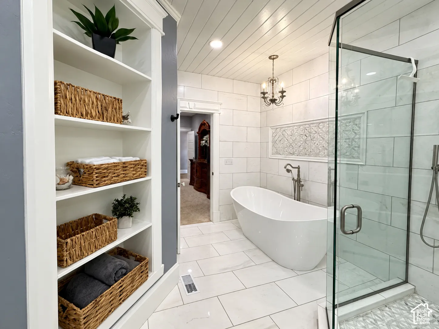 Spa-inspired primary bathroom featuring a freestanding soaking tub, frameless glass walk-in shower enclosure with subway tile surround, white shiplap ceiling, recessed lighting, and custom built-in shelving with woven storage baskets