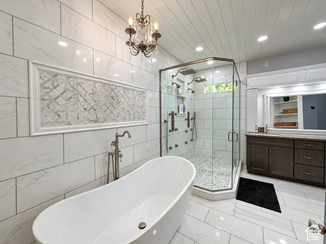 Spa-like primary bath with a freestanding soaking tub, marble mosaic accent wall andoversized glass walk-in shower.