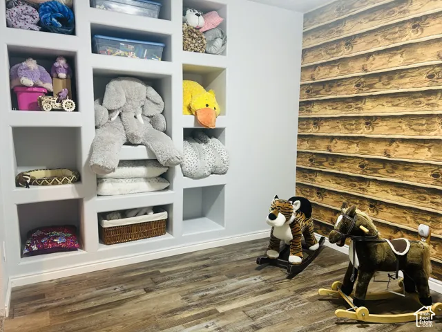 Playroom with built-in cubby shelving and a rustic log-cabin-style accent wallpaper