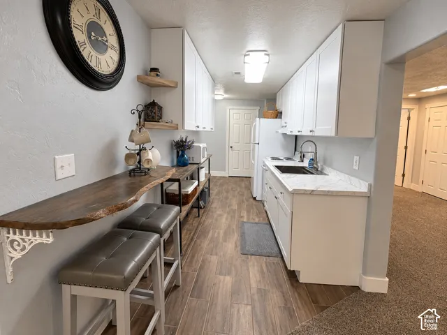Second kitchen with white shaker cabinetry, large farm sink, a live-edge wood breakfastbar and floating shelves, ideal for guests and gatherings.