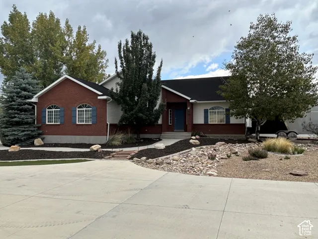 Red brick rambler with smokey blue wooden shutters, mature trees and low-maintenancelandscaping.