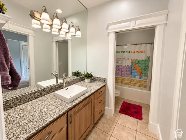 Shared Jack-and-Jill bath with a granite vanity, vessel sink and large mirror, plus a separatetub and toilet room so two people can get ready at once.