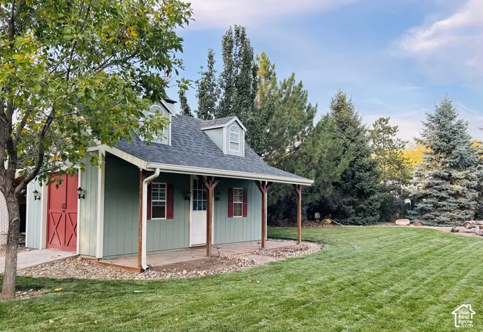 Storybook-style outbuilding with a timber-post covered porch, paver patio, dormerwindows, a cupola with weathervane, red barn doors and lantern-style sconces, with endlesspossibilities as a workshop, studio or retreat.