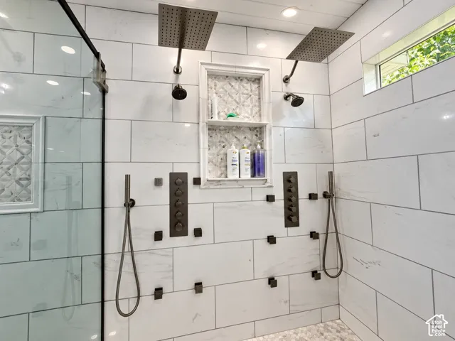 Luxurious dual shower system with two rainfall, two standard shower heads, twohandheld sprayers, individual control panels, multiple body sprays and a mosaic-tiled niche.