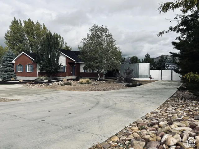Expansive concrete driveway with room for trailers, toys and guests, leading to gated RVparking, with drought-tolerant river rock landscaping, mature trees and mountain views.