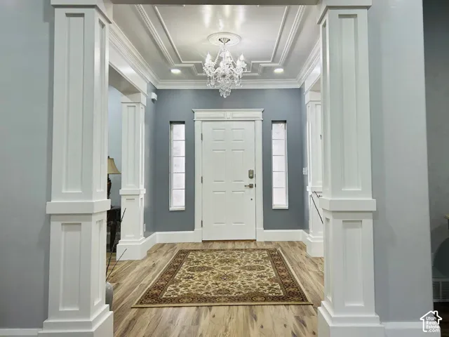 Elegant foyer framed by stately craftsman-style columns, with a crystal chandelier andceiling medallion.