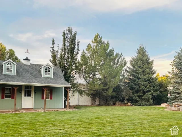 Private backyard with a sprawling lawn, mature evergreens and a charming outbuildingwith a covered porch, dormers and a cupola.