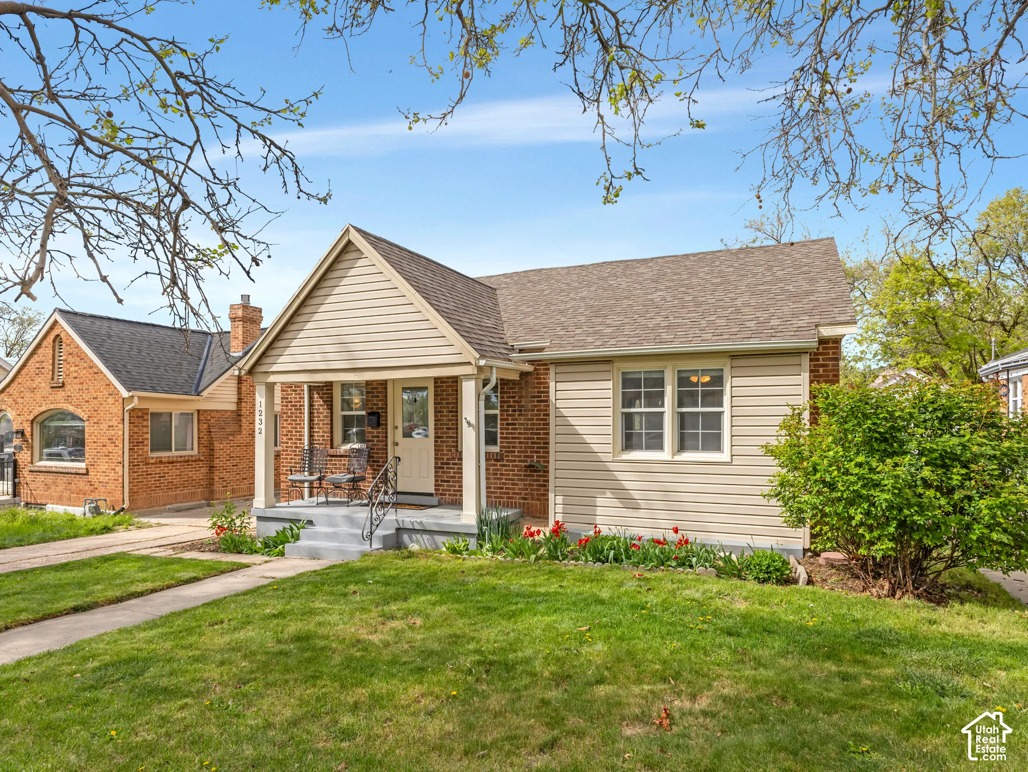 Brick and siding exterior with a covered front porch, concrete steps, and wrought iron railings