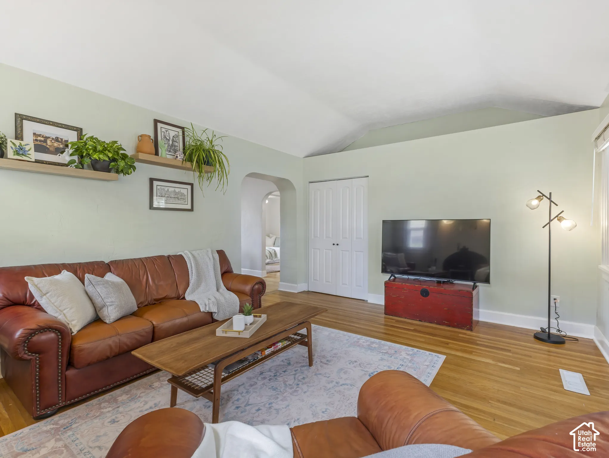 Hardwood flooring, vaulted ceiling, arched doorway, and a built-in closet with double doors