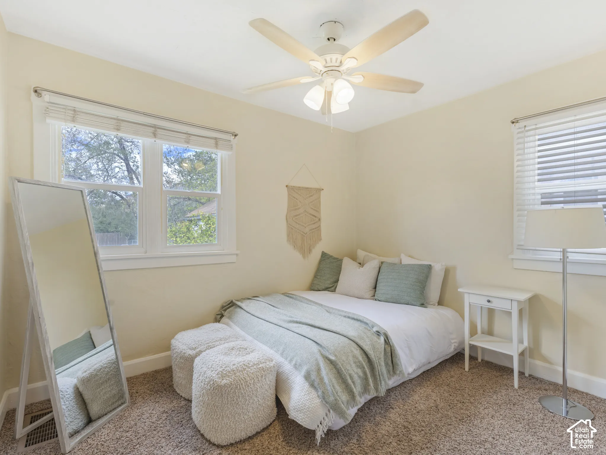 Ceiling fan with integrated lighting, dual pane window, window blinds, light-colored wall paint, and textured carpet flooring