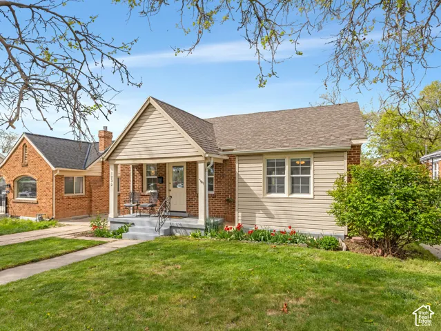 Brick and siding exterior with a covered front porch, concrete steps, and wrought iron railings