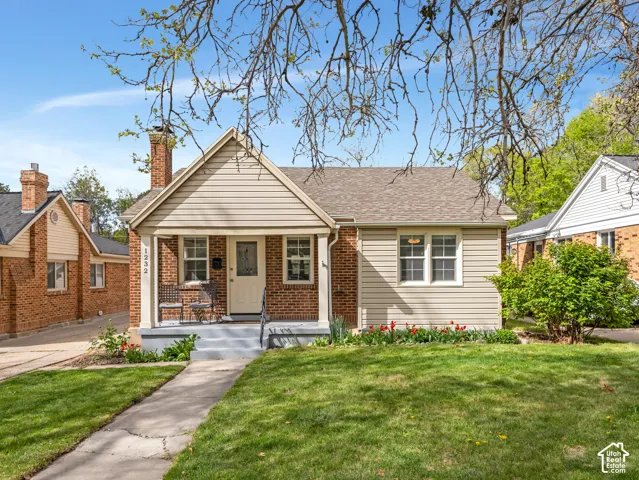 Brick and siding exterior with a covered front porch, gabled roofline, and front yard with mature landscaping