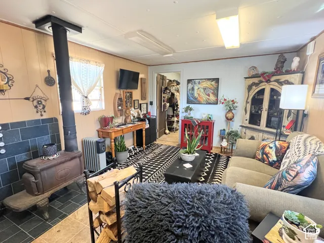 Wood-burning stove with a black tile surround, wood-finish flooring, and a wall-mounted light fixture