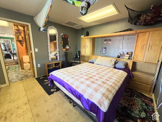 Wood-finish flooring with a built-in headboard unit featuring integrated cabinetry and shelving