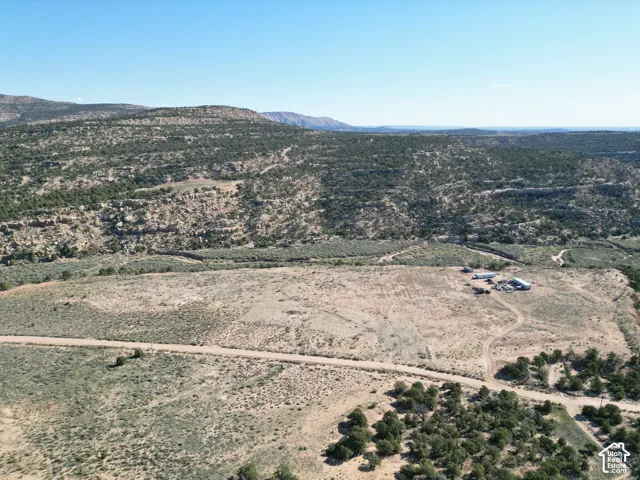 Expansive undeveloped land featuring a cleared building site, multiple outbuildings, and natural desert landscaping with scattered trees