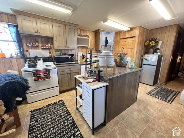 Kitchen featuring wood-finish cabinetry, tile flooring, and a central island with a stone-finish countertop