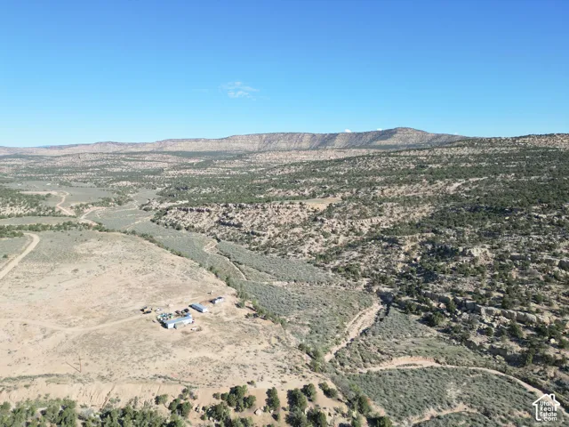 Expansive desert landscape featuring natural terrain, distant mountains, and scattered structures