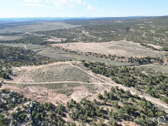Expansive rural landscape featuring a distant structure and unpaved access paths