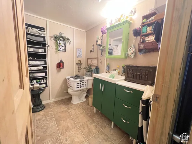 Floor-mounted toilet, vanity with sink, and tile flooring