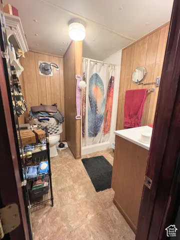 Wood paneling throughout, tile-finish flooring, built-in vanity with white countertop, white toilet