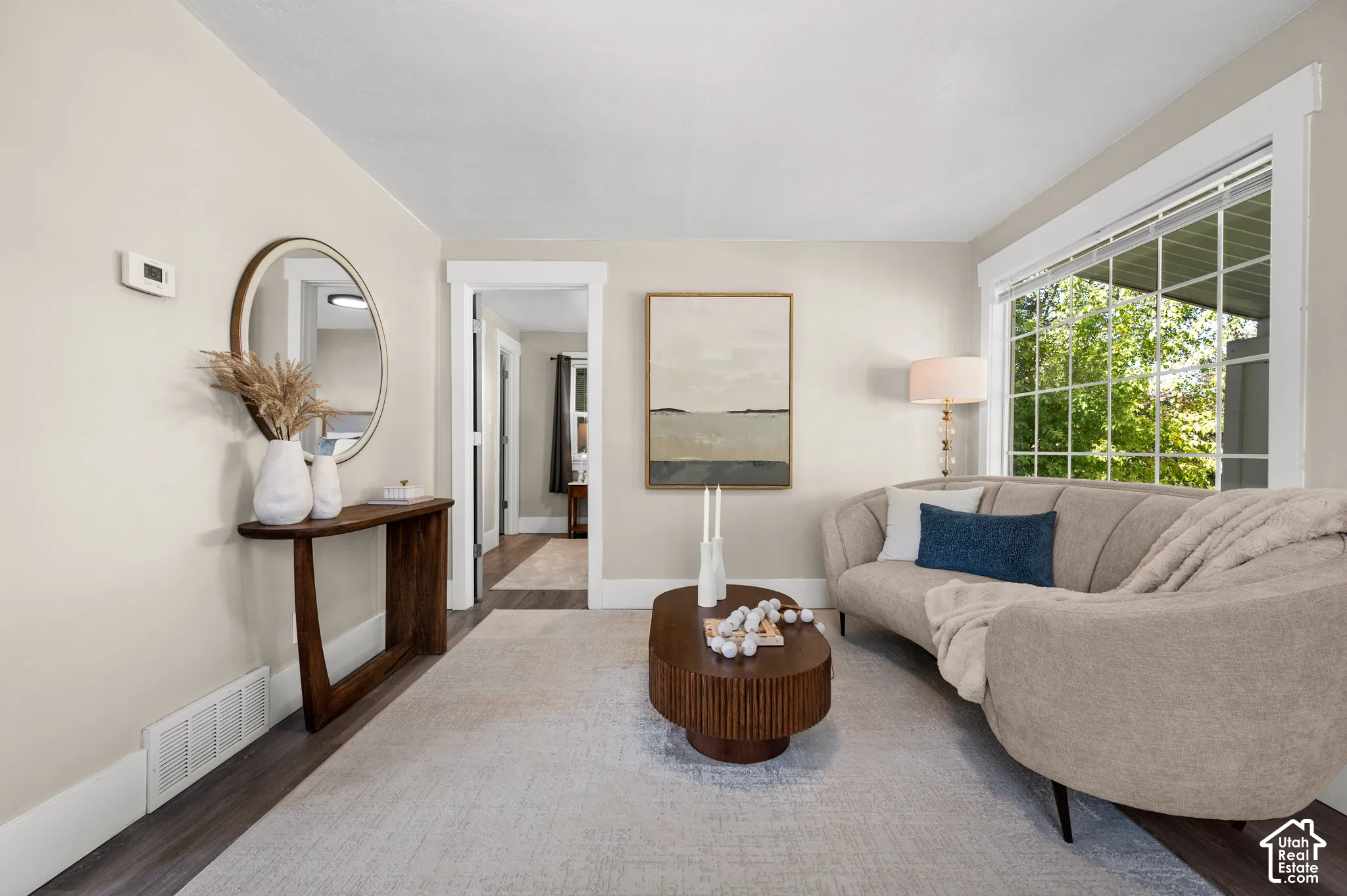 Wood-finish flooring, light-toned wall paint, crisp white trim, and a large multi-pane window