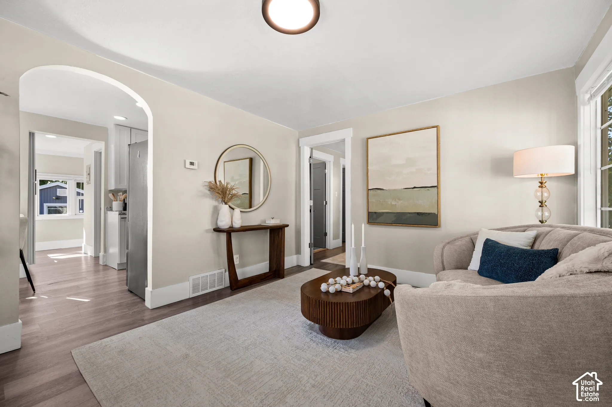 Light wood-finish flooring, arched doorway, and white trim