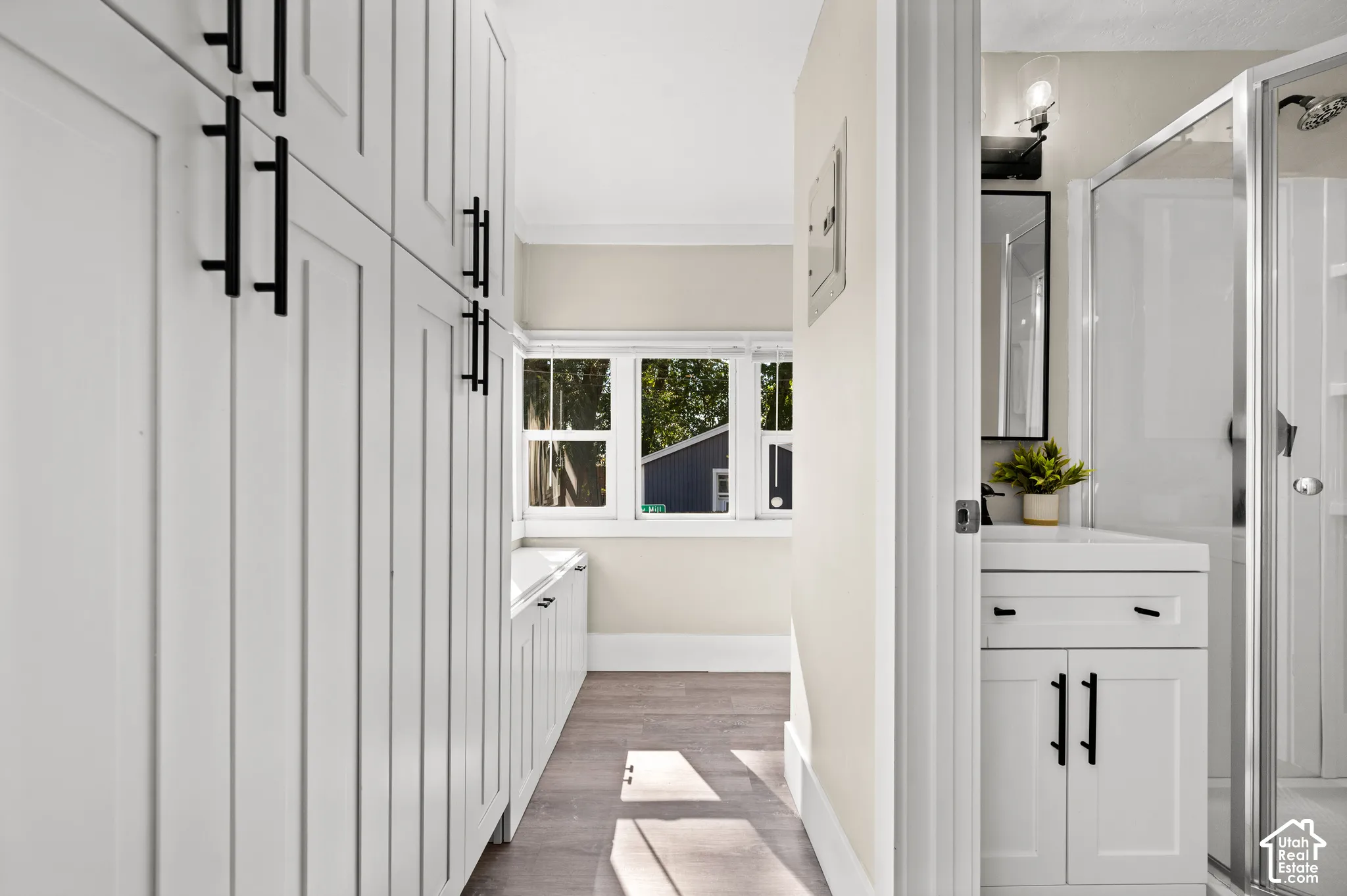 Extensive built-in cabinetry with matte black hardware, wood-finish flooring, and multiple windows