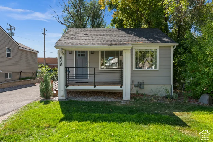 Gray exterior siding with white trim, dark gray front door, and a covered porch featuring black horizontal railings