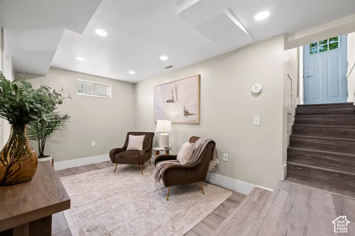 Recessed ceiling lighting illuminates a versatile finished space featuring wood-finish flooring and a light-toned wall color