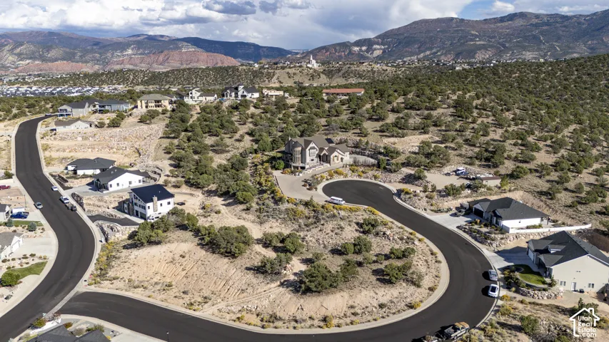 Paved curvilinear road, homes with dark roofs, natural desert landscaping, and distant mountains