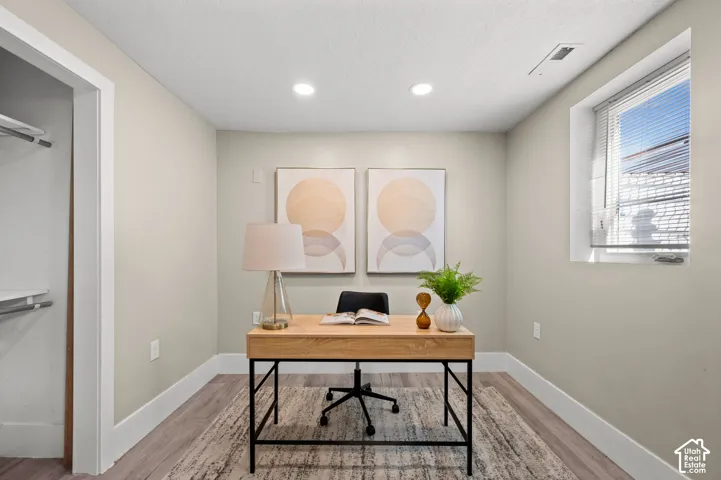 Recessed ceiling lighting, light wood-finish flooring, and a window with blinds