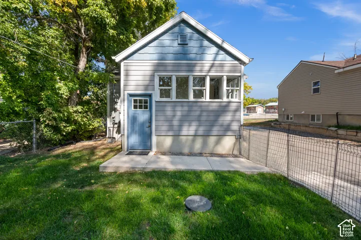 Exterior featuring fiber cement siding, a blue paneled door with grid lite, multiple windows, and a concrete patio