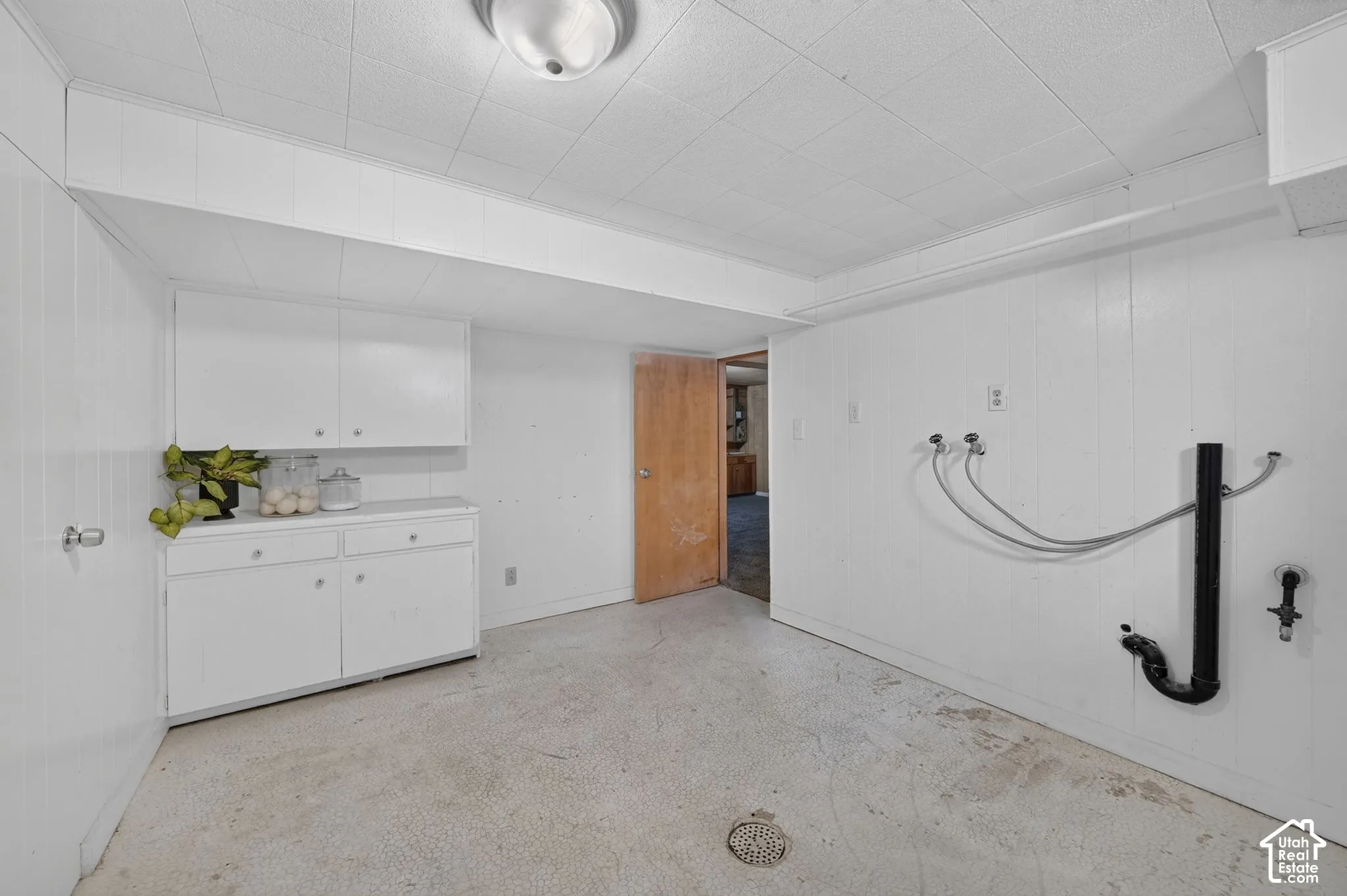 White paneling walls, built-in white cabinetry, concrete flooring, and ceiling-mounted light fixture