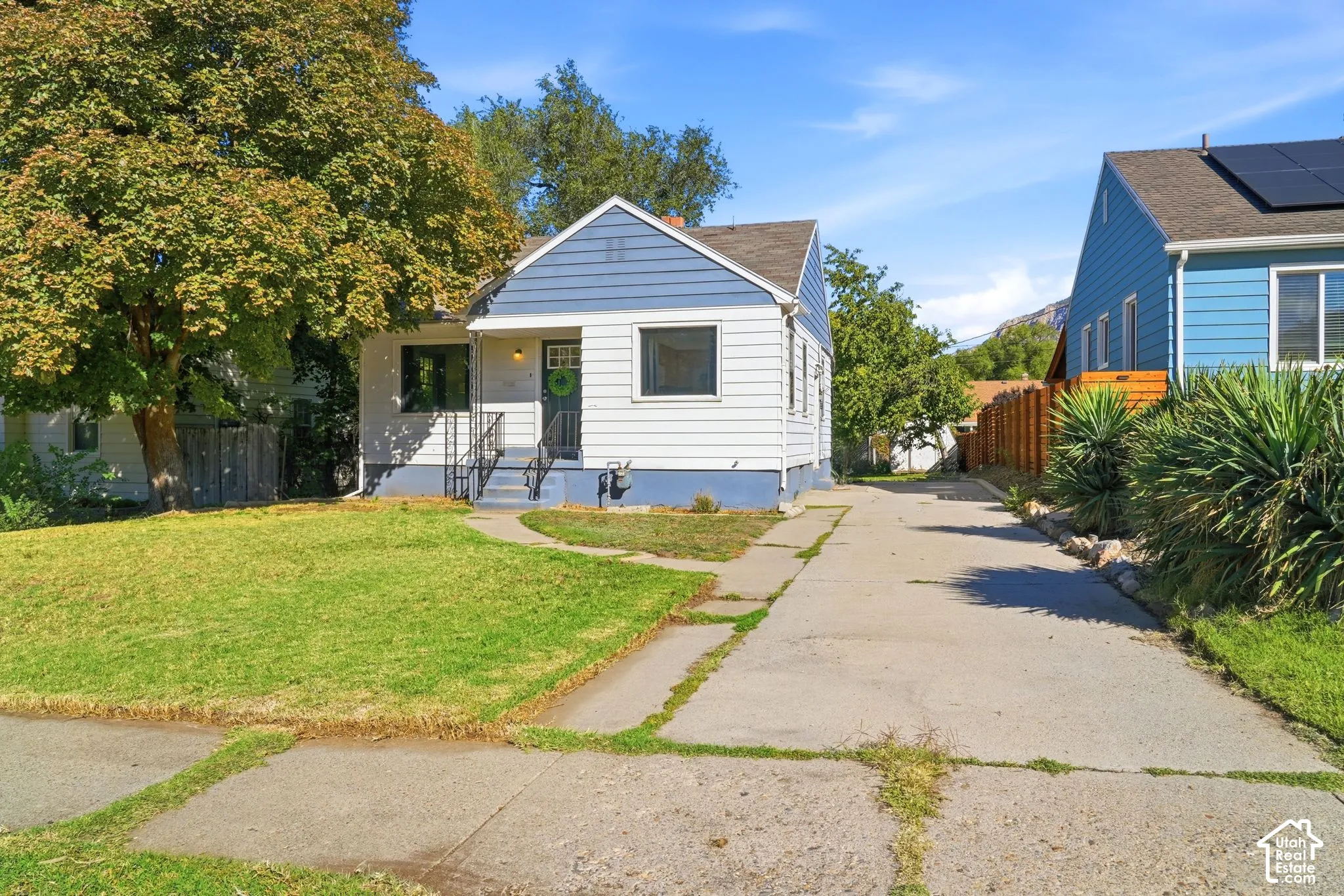 White siding exterior with a blue gable accent and a concrete walkway