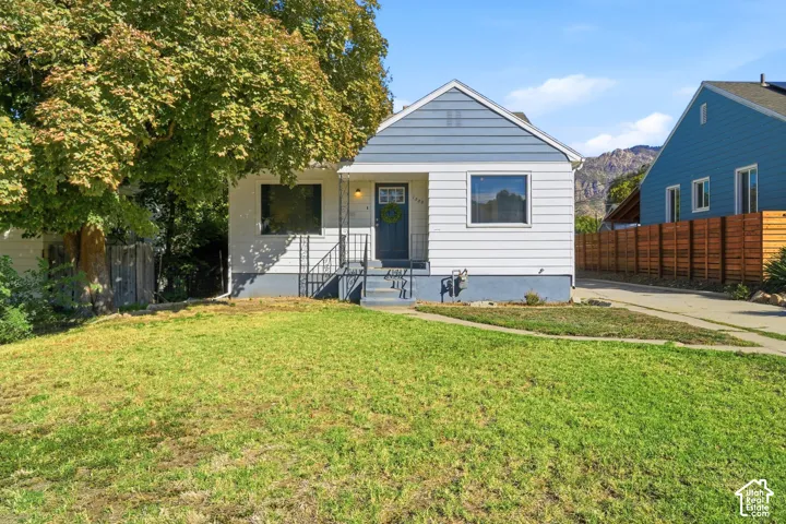 Charming cottage-style home featuring a freshly updated white exterior with horizontal siding, a peaked roofline, and black-trimmed windows