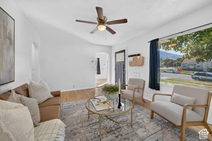 Bright living area featuring wood-finish flooring, a ceiling fan, and a large window with mountain scenery